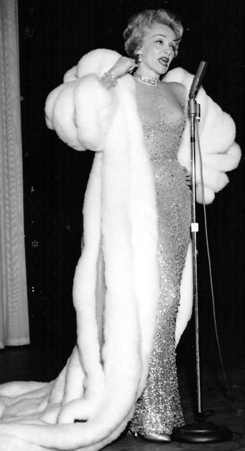 Marlene Dietrich con un lungo abito da sera e pelliccia canta in tournée, anni cinquanta circa