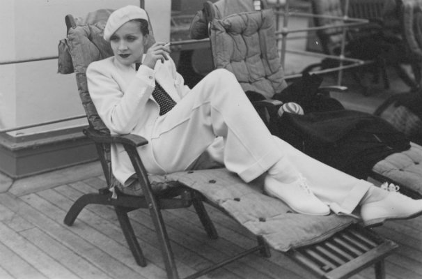 Marlene Dietrich in viaggio su un transatlantico, seduta su una sdraio indossa un completo bianco da uomo, 1933