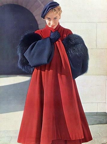 La modella indossa un ampio cappotto rosso di Christian Dior con inserti di pelliccia blu navy e cappello e guanti dello stesso colore