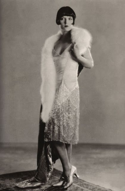 L'attrice Louise Brooks indossa un abito da sera chiaro e un mantello di velluto bordato di pelliccia. Chanel, anni '20