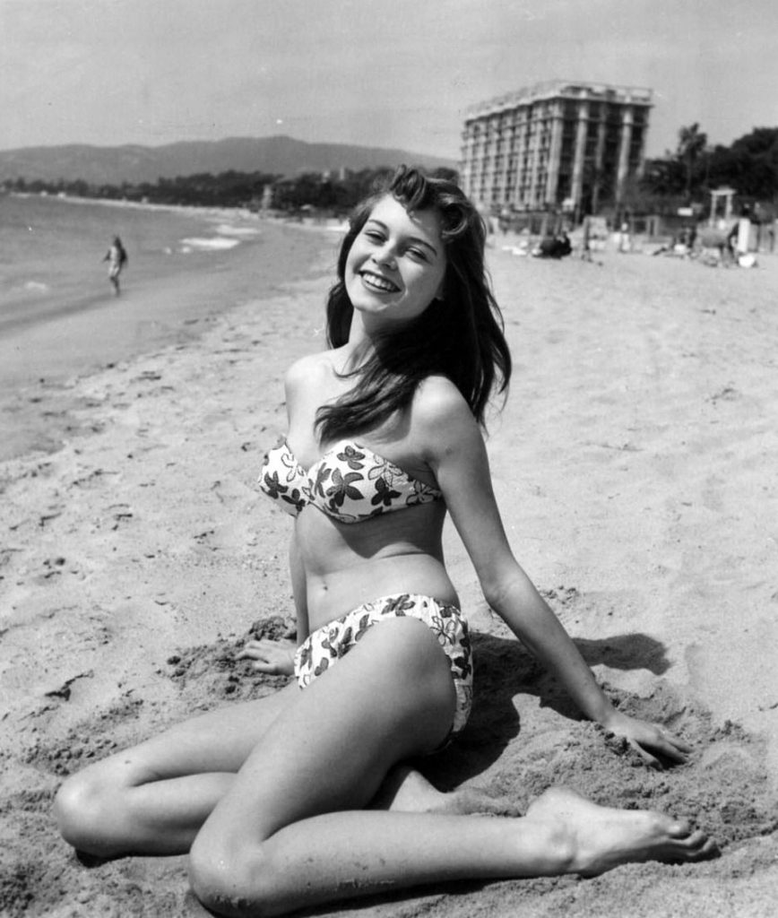 Brigitte Bardot giovanissima, in posa sulla sabbia mentre indossa un bikini a fiori, 1952 circa