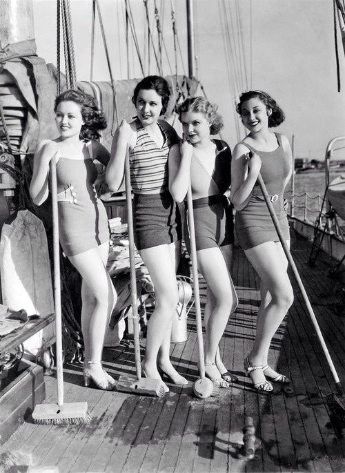 Quattro ragazze in costume da bagno fotografate con le ramazze per pulire il pavimento della barca, anni Trenta