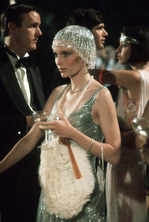 Mia Farrow indossa abito e copricapo di paillettes con collana di perle e ventaglio nel fil "Il Grande Gatsby", 1974